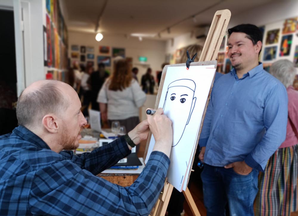 Daiel working on a live portrait of a man at an exhibition opening